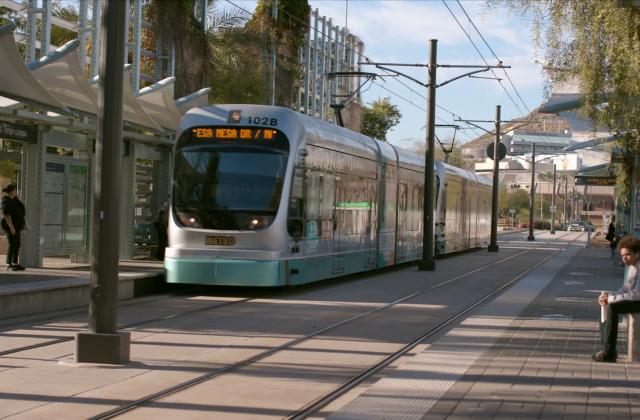 A metro pulls into a station. Passengers wait for the train.